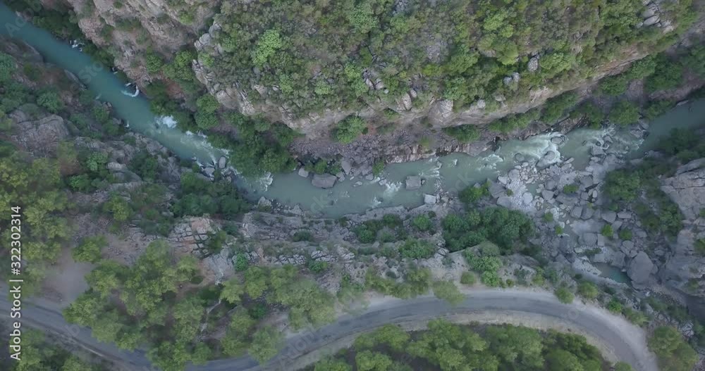 Top view on the canyon with a river in it and a road with a car driving, 4k