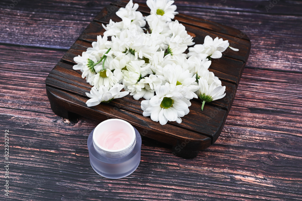 Fototapeta premium The concept of natural cosmetics. flowers and a jar of cream. heart-shaped chamomiles and a jar of cream. View from above. Natural cosmetic. place to record.