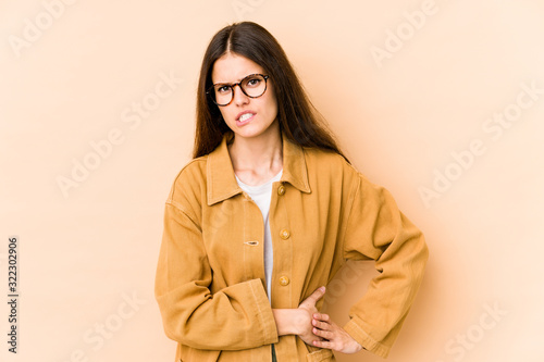 Young caucasian woman isolated on beige background having a liver pain, stomach ache.