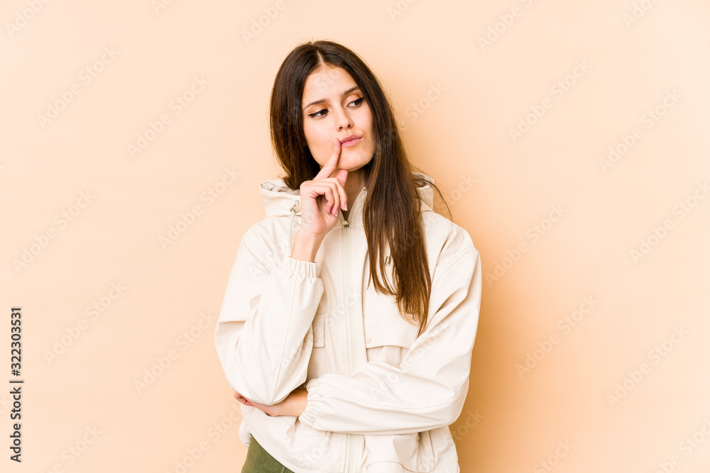 Young caucasian woman isolated on beige background looking sideways with doubtful and skeptical expression. Young caucasian woman isolated on beige background looking sideways with doubtful and skeptical expression.