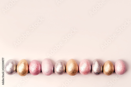 Colored painted pearl chicken and quail eggs of pink, silver, golden color on pastel background. Minimalistic creative idea easter festive flat lay banner. Copyspace for text