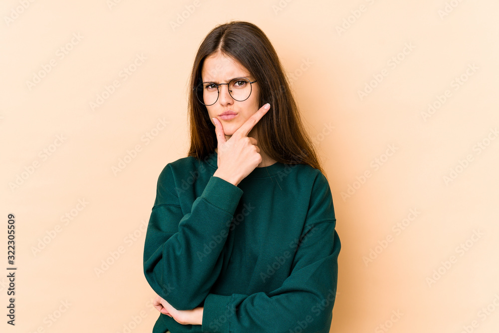 Young caucasian woman isolated on beige background contemplating, planning a strategy, thinking about the way of a business. Young caucasian woman isolated on beige background contemplating, planning a strategy, thinking about the way of a business.
