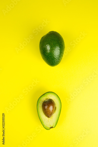 Green fresh avocado on isolated yellow background. Vitamin, vegan food concept