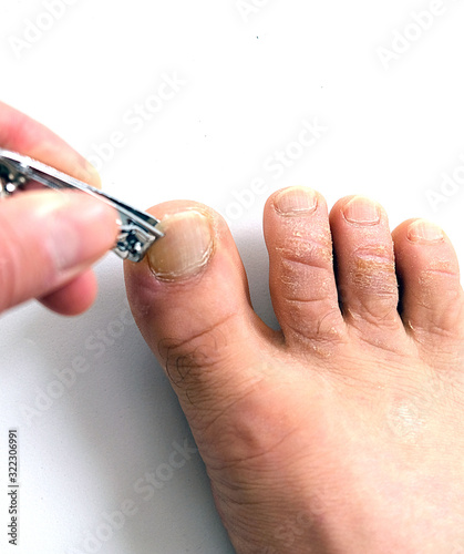 on the white floor  a person cuts his toenails 