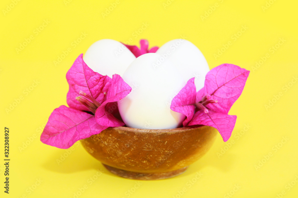 festive white eggs and natural flowers of pink bougainvillea in decorative wooden plate