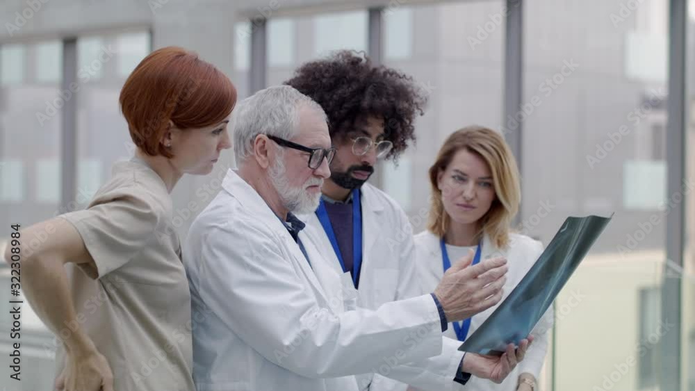 Group of doctors looking at X-ray on medical conference, discussing issues. Group of doctors looking at X-ray on medical conference, discussing issues.