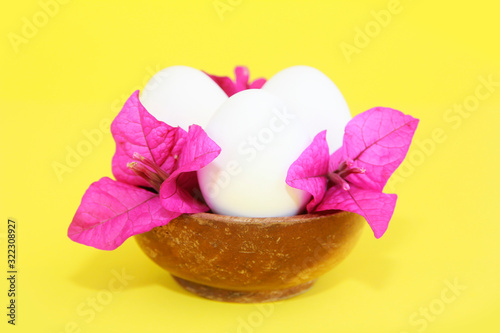 festive white eggs and natural flowers of pink bougainvillea in decorative wooden plate
