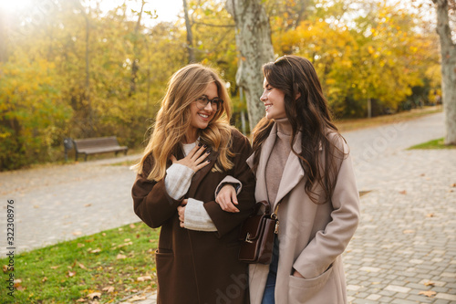 Cheery optimistic young women friends walking