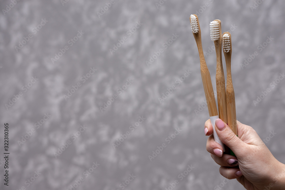 Three white bamboo toothbrushes in a hand on a gray concrete background. close-up. soft light. friendly eco. Three white bamboo toothbrushes in a hand on a gray concrete background. close-up. soft light. friendly eco.