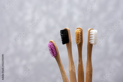 Four multi-colored bamboo toothbrushes on gray concrete background. close-up. soft light. friendly eco. ecological product. family set