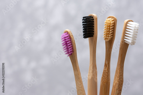 Four multi-colored bamboo toothbrushes on gray concrete background. close-up. soft light. friendly eco. ecological product. family set