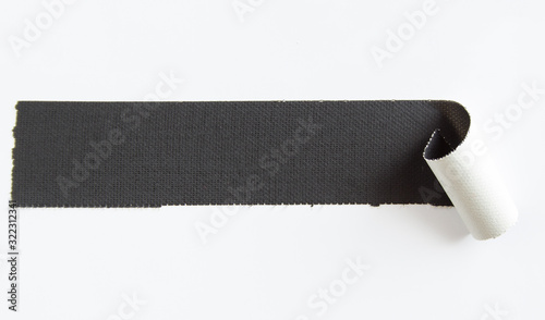 Fotografie Peeling piece of black matte cloth gaffer tape isolated on white background