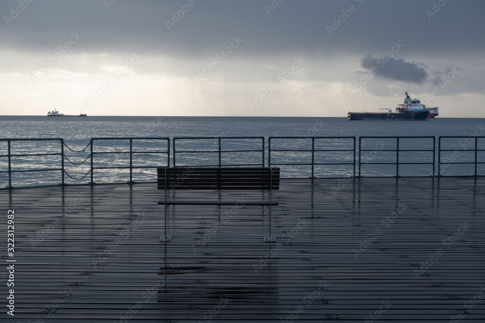 Fototapeta premium Promenade benches after rain and cloudy sky
