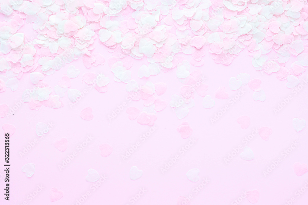 Heart made of pink confetti on pastel background. Festive romantic gentle abstract background for the design. Valentine's Day. Top view, flat lay composition. Copy space for text.