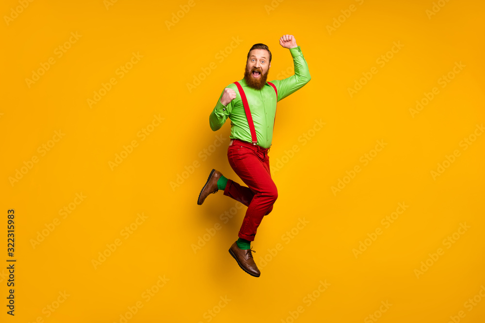 Full size photo of ecstatic cheerful man win discount lottery feel rejoice jump raise fists scream yeah wear good look trousers isolated over shine bright color background