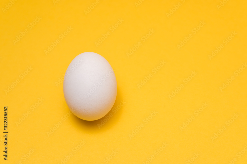 one egg in center of yellow background with dramatic light. design idea one egg in center of yellow background with dramatic light. design idea