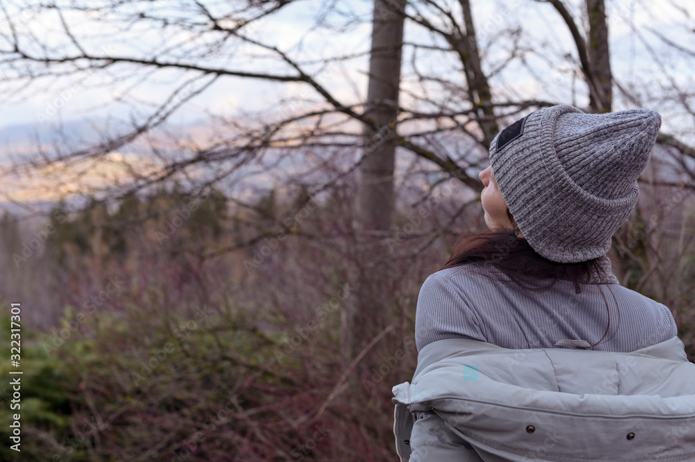 A girl in a hat and jacket stands on a panorama overlooking the hills and the village. Tourism and travel concept. Copy space A girl in a hat and jacket stands on a panorama overlooking the hills and the village. Tourism and travel concept. Copy space