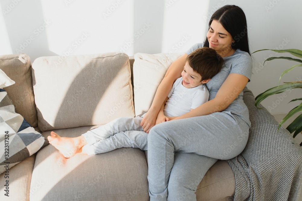 Young mother with her 4 years old little son dressed in pajamas are relaxing and playing in the bed at the weekend together, lazy morning, warm and cozy scene. Young mother with her 4 years old little son dressed in pajamas are relaxing and playing in the bed at the weekend together, lazy morning, warm and cozy scene.