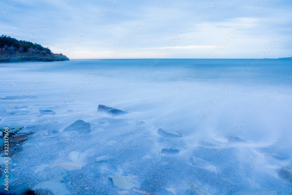 Storm surges at slow shutter speeds on a pebble-sandy beach, the resort of Gelendzhik, the twilight