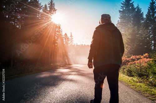 man walking on country road at sunset