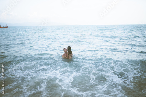 Beautiful and young guy and girl swim and enjoy in the ocean or in the sea. Honeymoon in the tropics of a husband and wife. Romance in hot countries. Wallow in the sand and be happy and in love. Lover