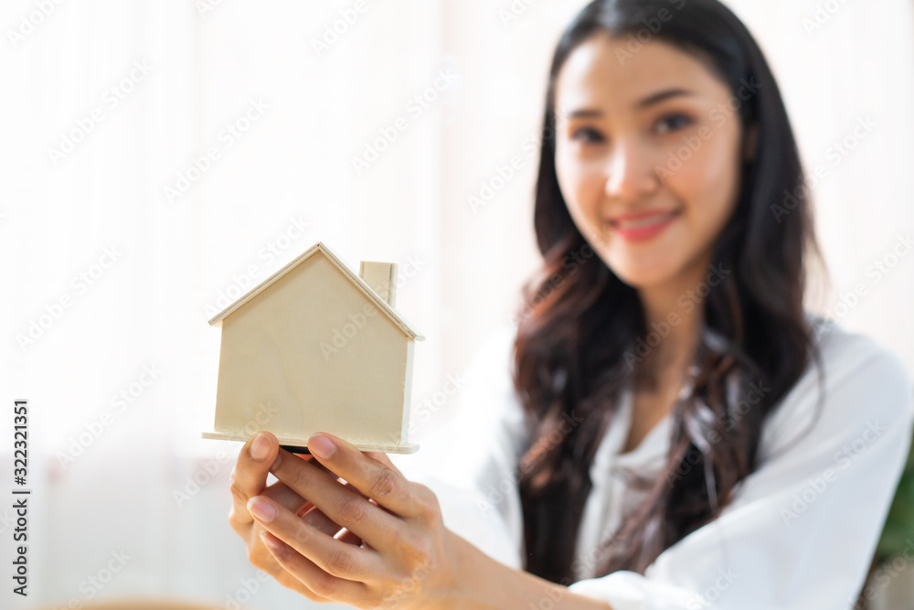 Happy Asian woman holding house model, focus on home asset, concept for business insurance, architecture building mortgage, residence buying, real estate agent, family property ownership, good living Happy Asian woman holding house model, focus on home asset, concept for business insurance, architecture building mortgage, residence buying, real estate agent, family property ownership, good living