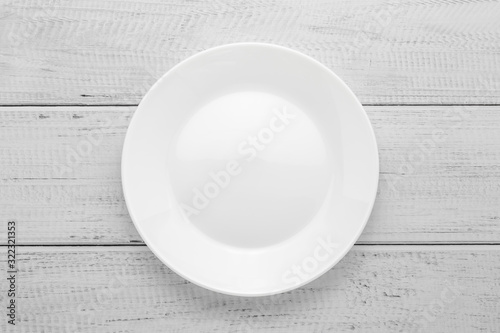 Empty white plate on gray wooden table. Top view. Wood board background.