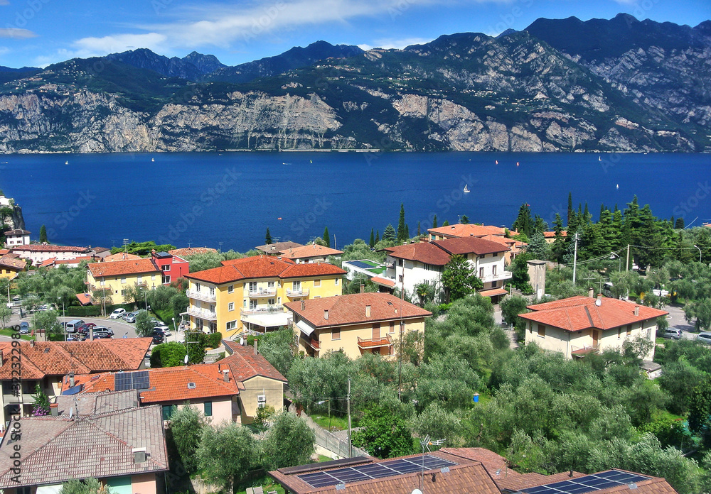 Monte Baldo, Italy - Brown tiled houses and trees in the city of Malcesine, Blue Lake Garda, in the summer afternoon.
