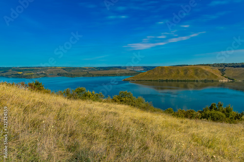 summer panoramic idyllic nature landscape scenic view of river surrounded by hill land outdoor environment and blue sky horizon background space