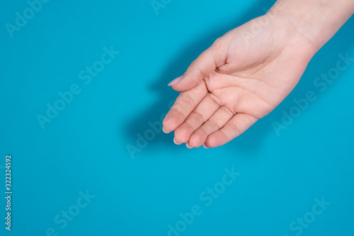 Closeup top view of one cupped empty female hand isolated on blue background.