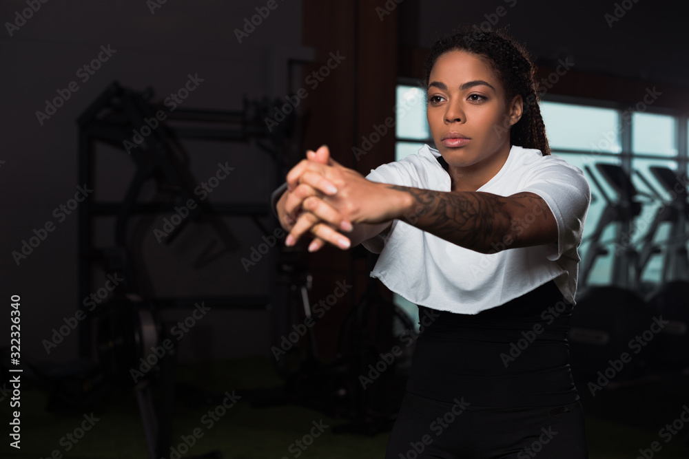 Selective focus of african american attractive woman clenching hands and training in gym Selective focus of african american attractive woman clenching hands and training in gym