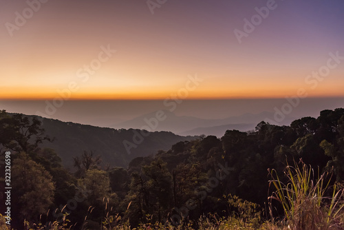 Sunrise at Doi Inthanon, mountain view misty morning of alone tree and many hills with red sky background.