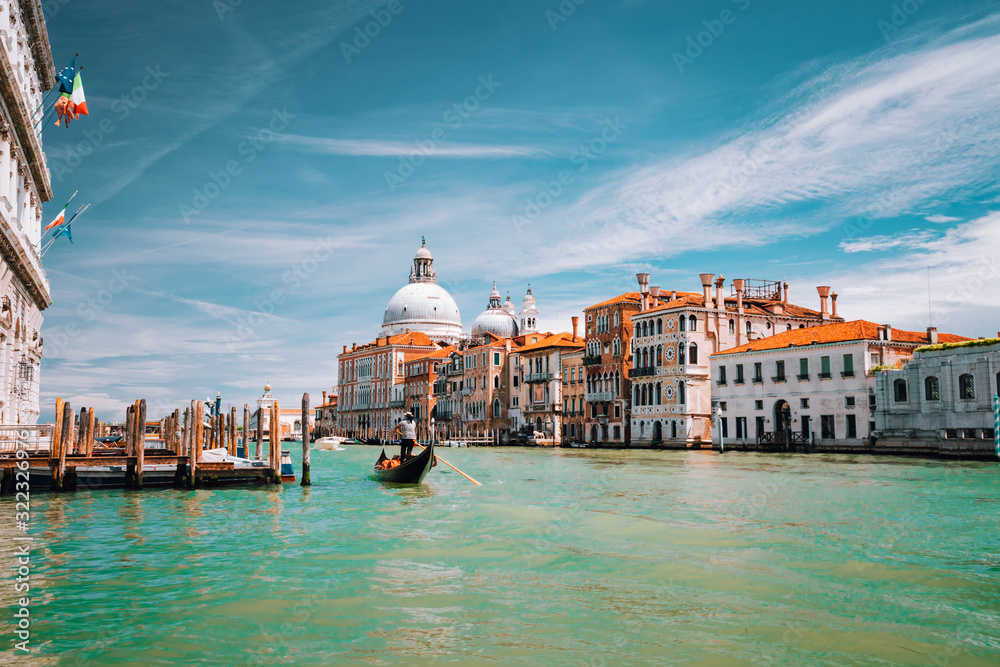 Venice, Italy. Tourist gondola trip on Grand Canal. Basilica Santa Maria della Salute against blue sky and white clouds
