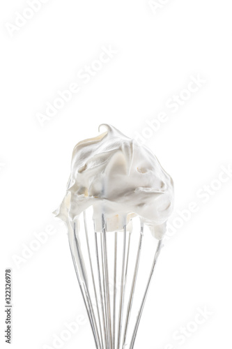 A close up of a slender whisk topped with whip cream peaks isolated against a bright white background. photo