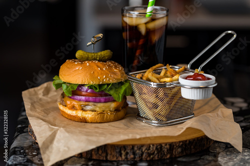 Obraz na plátně Front facing close up view of a burger and fries ready for eating with a soft drink in behind