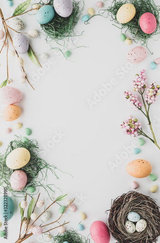 Top down view of an Easter border flat lay including robin's eggs, chocolate eggs and nests in desaturated colours.