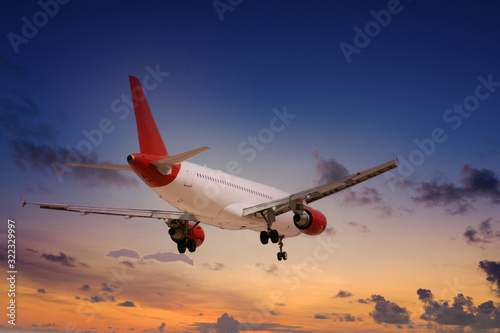A red and white commercial airline landing under a cloudy sky