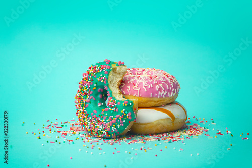 Obraz na płótnie Donuts (doughnuts) of different colors on a green background with multi-colored festive sugar sprinkles