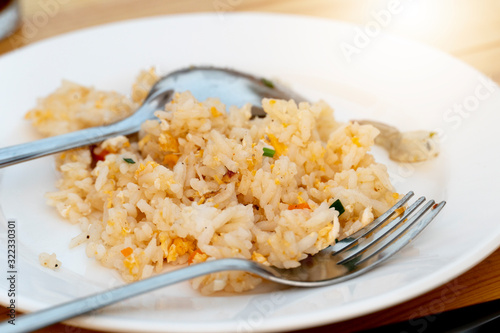 Fried rice on a plate with a spoon and fork being eaten.