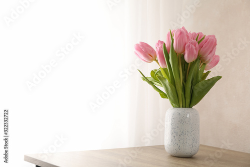 Tulips in vase on wooden background, space for text
