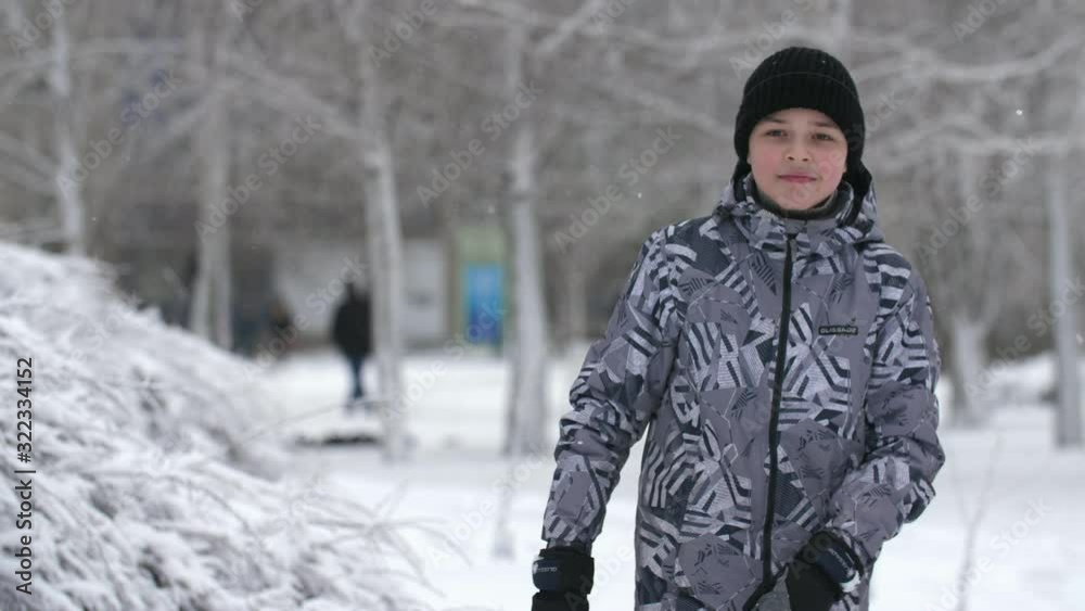A smart boy in a black hat standing and doing dab in a snowy park in winter A smart boy in a black hat standing and doing dab in a snowy park in winter