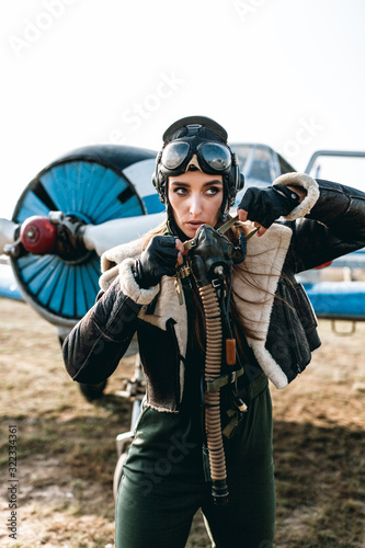 close-up of an aviator wearing a special headgear to protect ears with glasses, wearing a mask with oxygen to protect her lungs from discharged vodka against the backdrop of an airplane