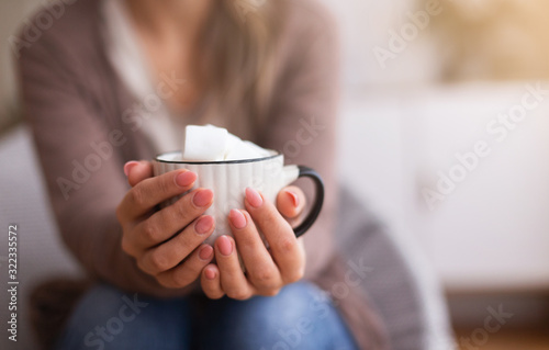Hot chocolate with marshmallows in female hands, close up