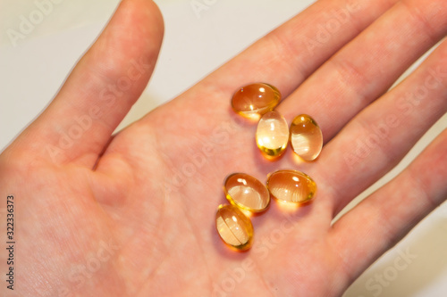 capsules of fish oil lie on a hand on a light background. view from above. vitamins for health.