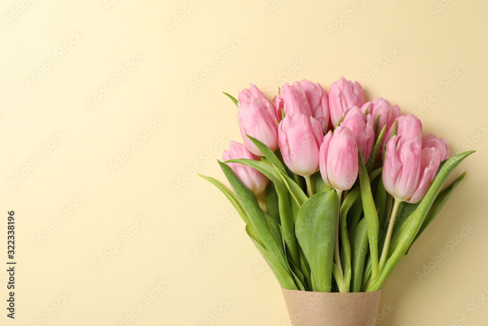 Tulips in craft paper on beige background, space for text