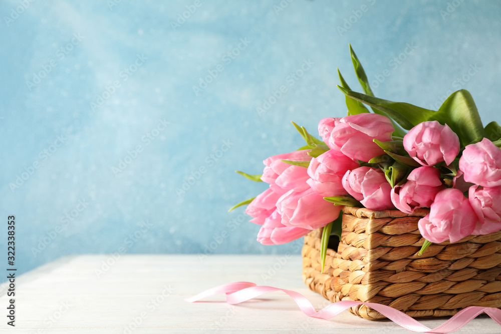 Basket with tulips against blue background, copy space