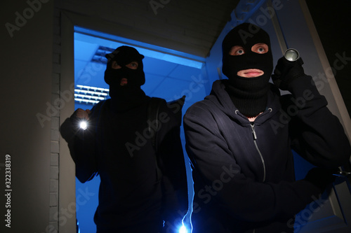 Fototapeta Naklejka Na Ścianę i Meble -  Thieves with flashlights breaking into house at night