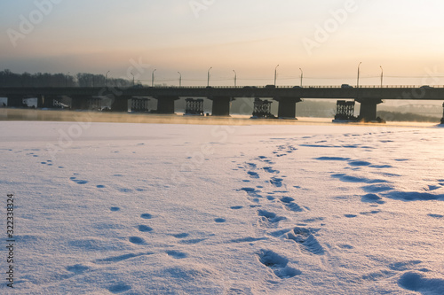 The tracks on the ice go to the bridge over the river