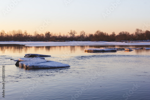 Ice floe in the middle of the river in the rays of the rising sun