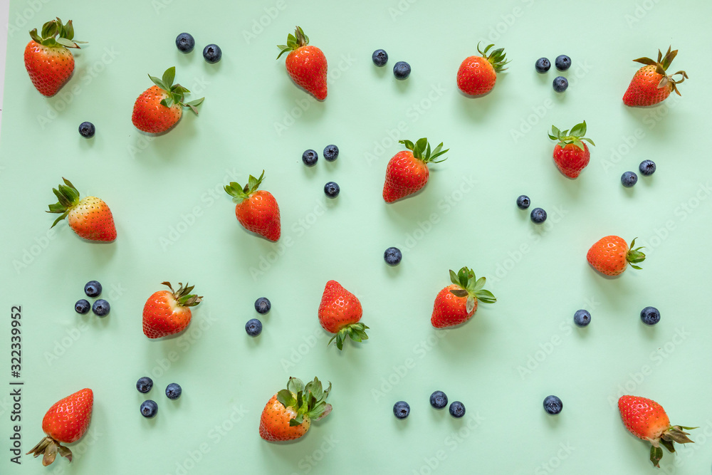 Strawberry and blueberry on pastel green background. Flat lay, top view of food Strawberry and blueberry on pastel green background. Flat lay, top view of food